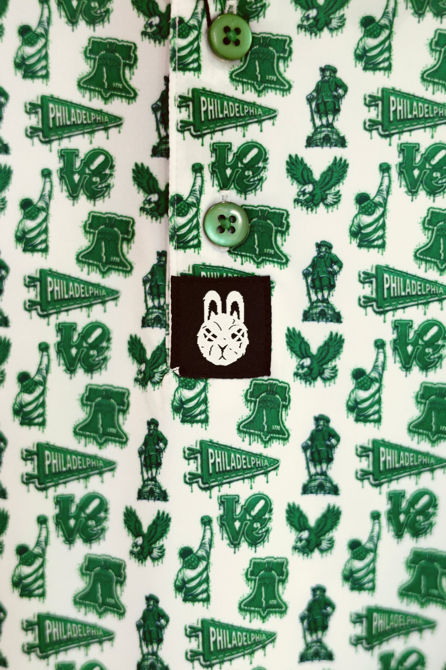 Front detail of The Bleeding Green Polo featuring Kelly green buttons, all-over Philadelphia-inspired graphics, and City Golf Co. logo tag.