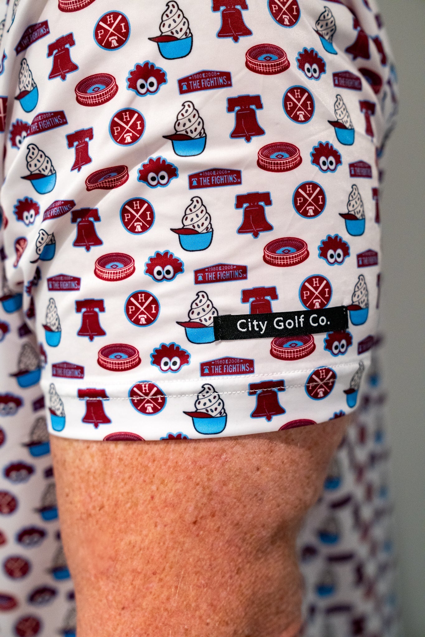 Close-up detail of City Golf Collective Philadelphia-inspired golf polo featuring retro all-over graphics, lightweight performance fabric, and branded City Golf Co. sleeve tag detail.
