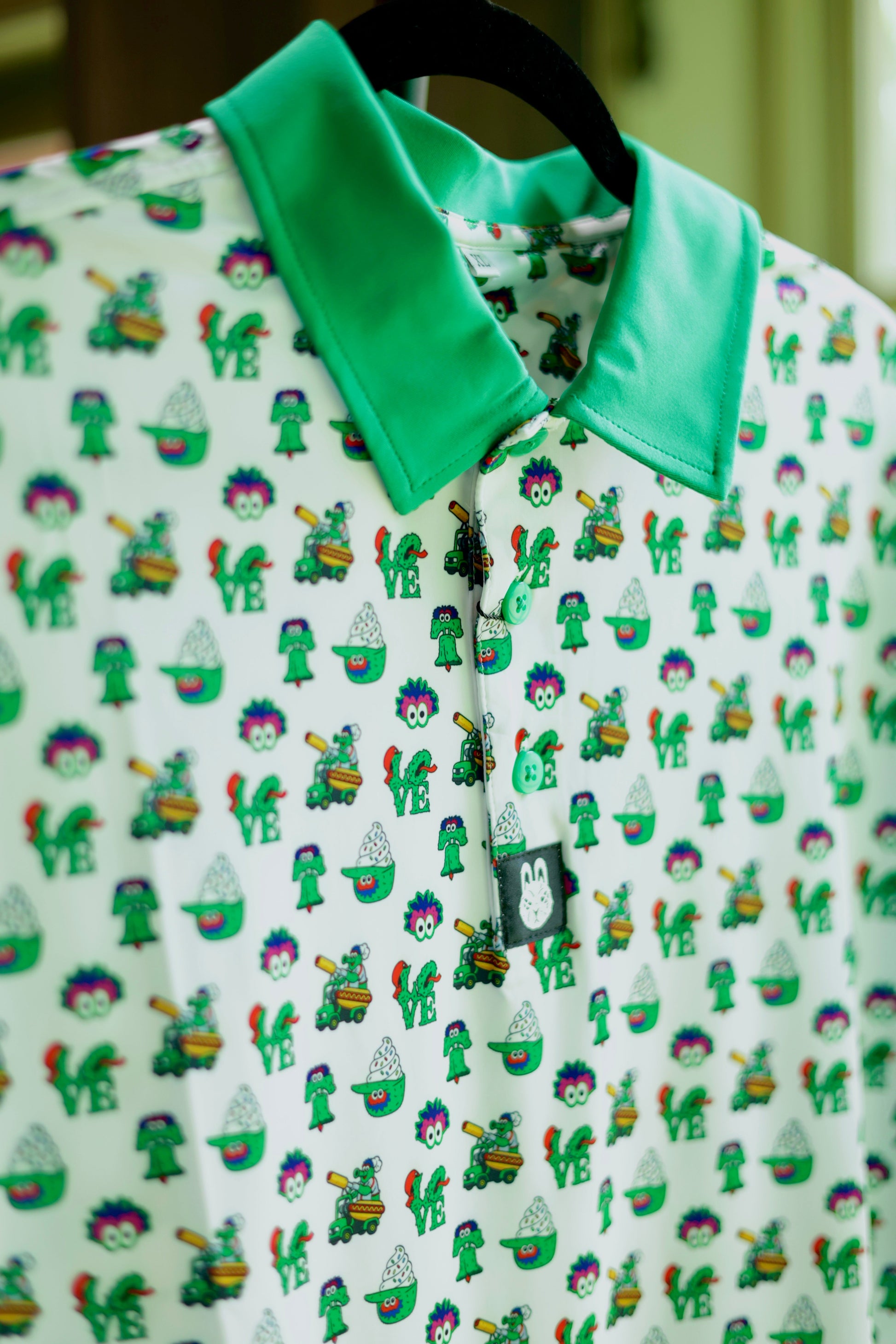 The Green Menace Polo featuring a white performance golf shirt with playful Philadelphia-inspired green mascot graphics, a vibrant green collar, and moisture-wicking fabric.