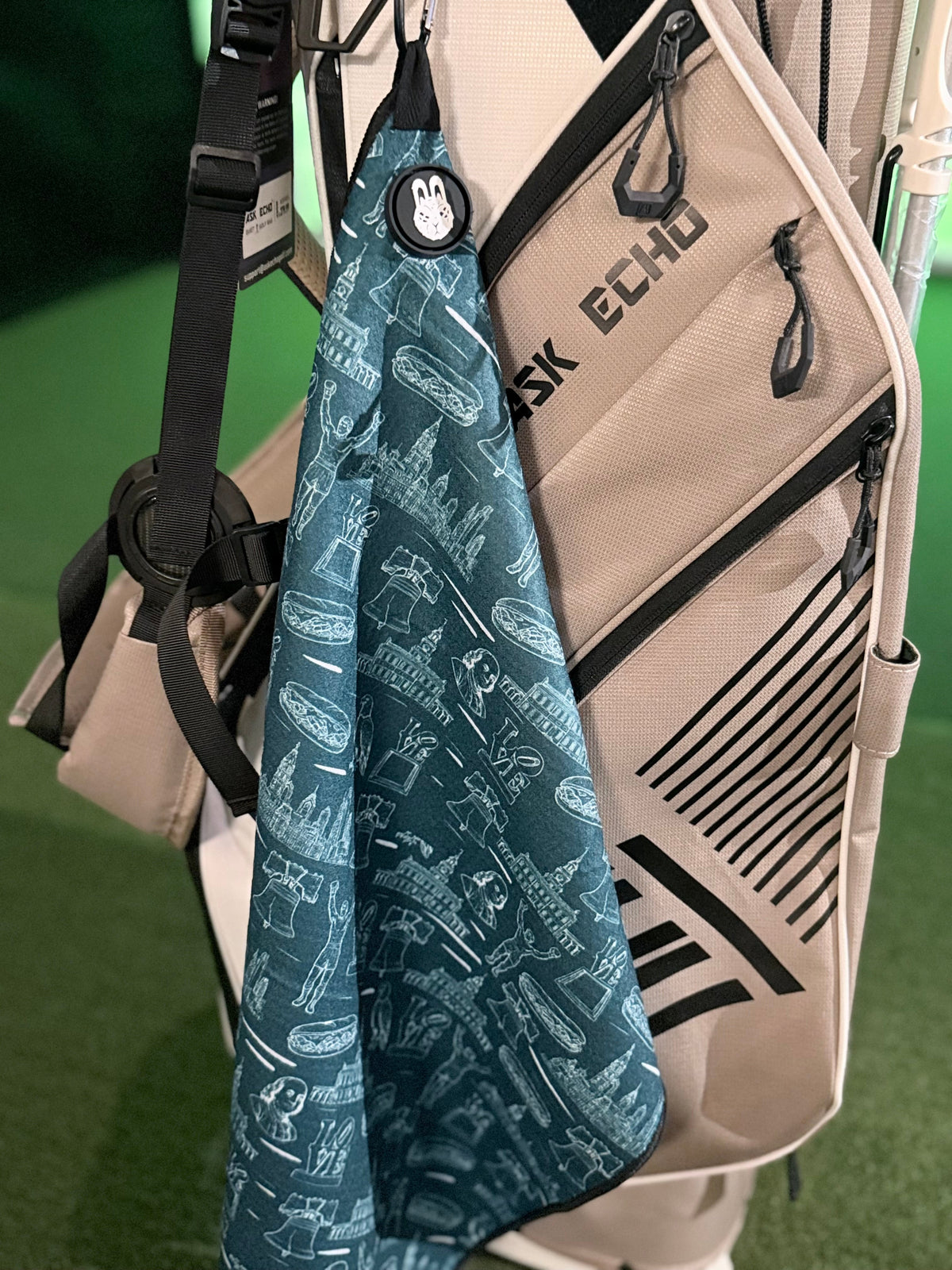 The Philly Heritage Golf Towel displayed on a golf bag with Philadelphia landmarks and sports-inspired illustrations.