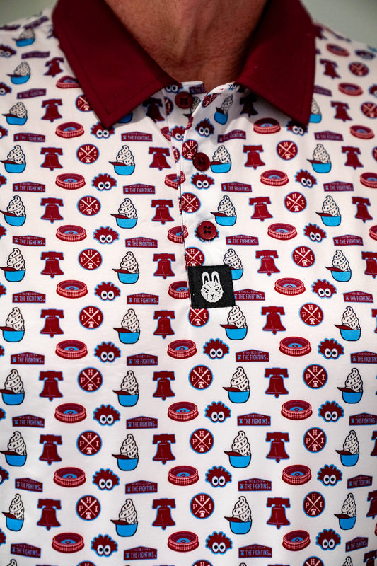 Close-up of City Golf Collective Philadelphia-inspired golf polo featuring an all-over print design with retro ballpark-inspired artwork, maroon collar, and performance fabric construction.