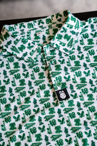 Close-up of white and green Philadelphia-themed performance golf polo featuring all-over city-inspired print and bunny logo tag