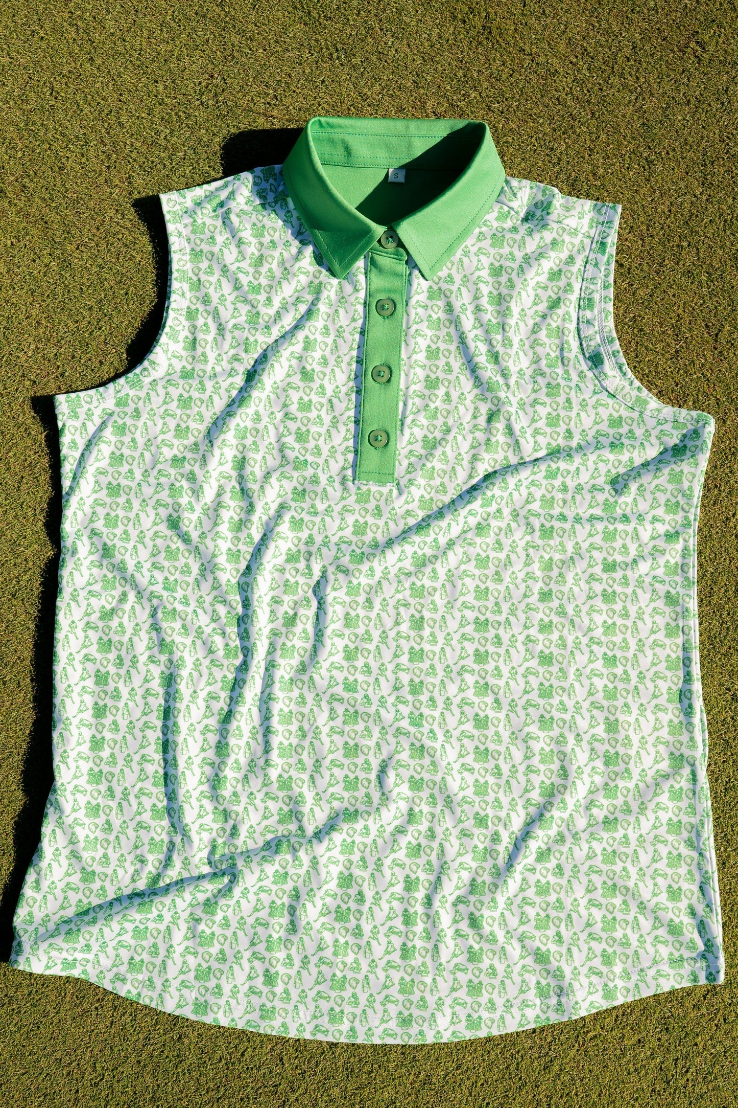 Birds & Beauties women’s golf polo by City Golf Collective laying flat on a putting green near a golf hole