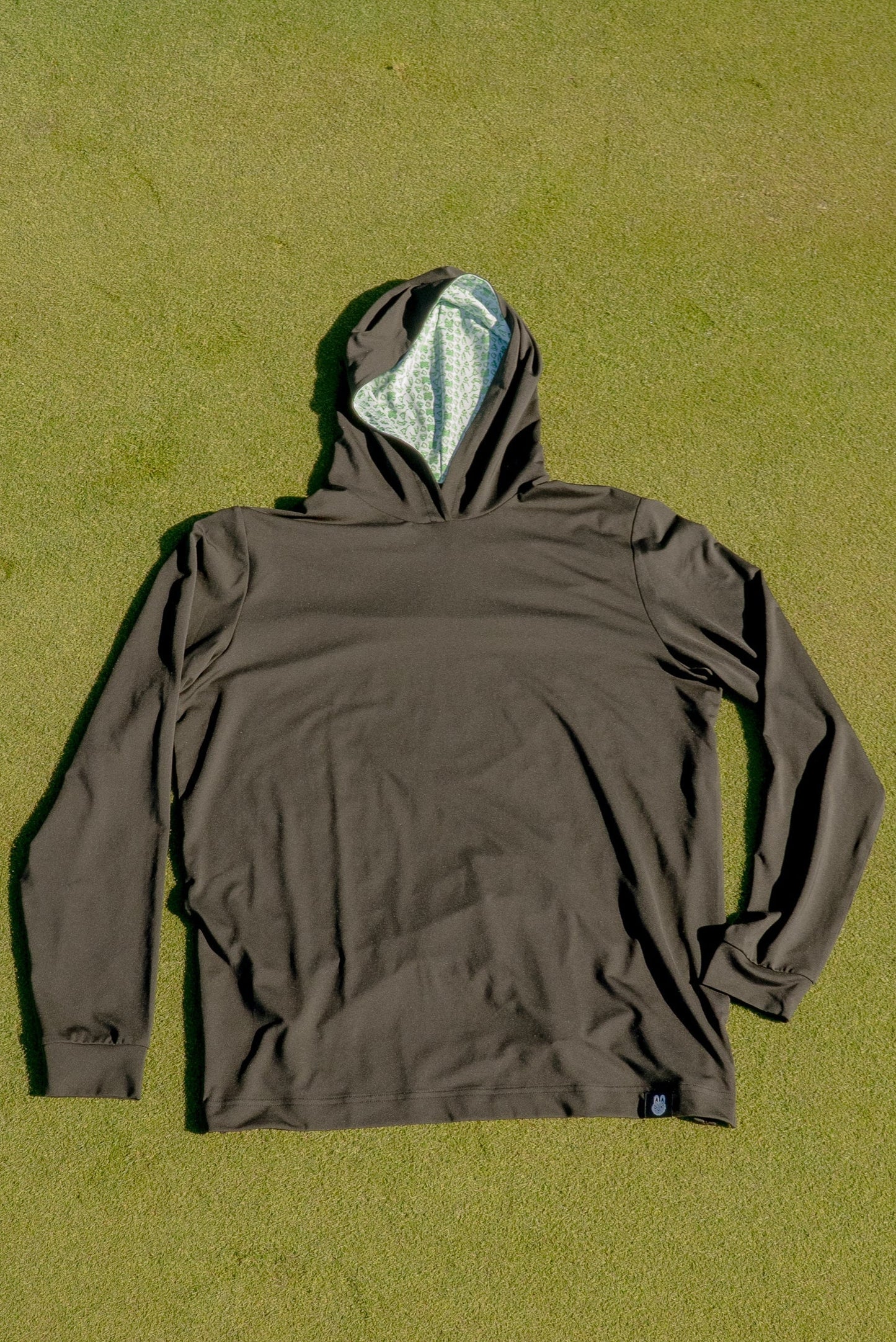Birds & Hoodies golf hoodie by City Golf Collective laid out on a golf putting green for a clean lifestyle shot.