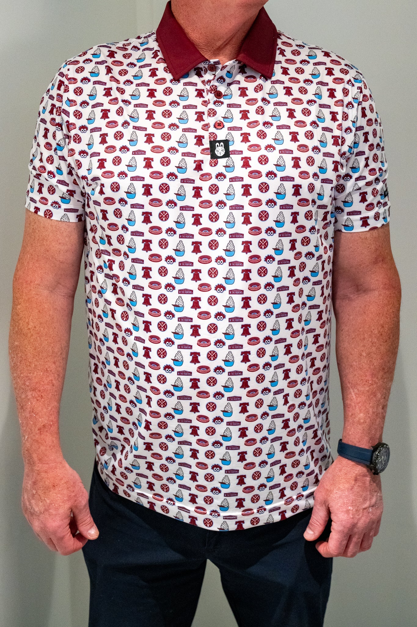 Front view of City Golf Collective Philadelphia-inspired performance golf polo featuring vintage-inspired all-over graphics, maroon collar, athletic fit, and lightweight performance material.