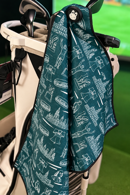 The Philly Heritage Golf Towel hanging on a golf bag, featuring iconic Philadelphia landmarks, vintage-inspired artwork and City Golf Collective bunny logo.